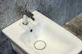 Hanging bidet with a chrome mixer against a backdrop of sleek gray tiles. Modern plumbing fixtures for a contemporary