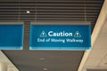 Hanging blue cation sign warning the end of a moving walkway