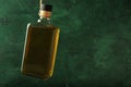 Hanging bottle of whiskey on color background. Concept of alcoholism