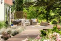 Hanging chair and pouf on wooden veranda in the middle of garden