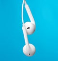 Hanging headphones on a white cable, modern gadget on a blue background