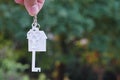 Hanging home key with house keyring with green garden background