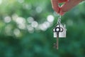 Hanging home key with house keyring with green garden background