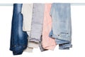 Hanging jeans isolated. Closeup of collection of five female various denim pants or colorful trousers on a clothes rail isolated