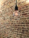 Hanging light bulb filament in front of brick wall Royalty Free Stock Photo