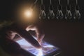 Hanging light bulbs with glowing one with hand touching screen Royalty Free Stock Photo