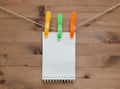 Hanging notebook with colored clothespins on wood background Royalty Free Stock Photo