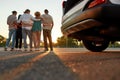 Backs of five young casually dressed friends standing together outside on a parking site casting shadows on a camera Royalty Free Stock Photo