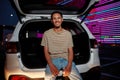 A well-dressed dark-skinned young latina man with a piercing smiling looking into a camera sitting in an opened car Royalty Free Stock Photo