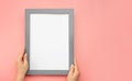 Hanging a photo frame mockup on pink wall. Picture frame mockup. Holding frame mockup. Photo Mockup. Female hands hold frame with Royalty Free Stock Photo