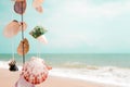 Hanging seashells decoration with tropical beach and blue sky background.