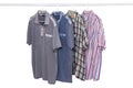 Hanging shirts isolated. Closeup of collection of four male various colorful t-shirts on a clothes rail isolated on a white