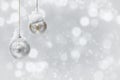 Hanging silver christmas balls covered snow on a blur light background with space for text