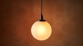 Hanging spherical lightbulb with warm glow on brown background. Royalty Free Stock Photo