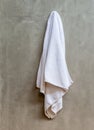 Hanging white towel draped on exposed concrete wall in the bathroom. Royalty Free Stock Photo