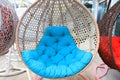 Hanging wicker chair, swing with blue cushion. Beautiful fashionable, modern garden, home furniture, rattan sofa Royalty Free Stock Photo