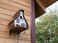 Hanging wooden bird house on the wall of a building. Concept of care for animals, avian welfare Royalty Free Stock Photo