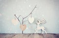 Hanging wooden hearts over and wooden rain deer decoration over wooden background. retro filtered image Royalty Free Stock Photo