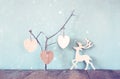 Hanging wooden hearts overand wooden raindeer decoration over wooden background. retro filtered image Royalty Free Stock Photo