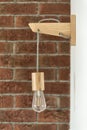 Hanging, wooden light shade lamp with bulb. Lighting bulb against a brick wall background Royalty Free Stock Photo