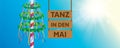 hanging wooden sign "tanz in den mai" maypole with colorful ribbons
