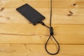 hangman noose made from an usb cable, connected to a generic smartphone, on wood boards background Royalty Free Stock Photo