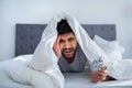 Hangover concept. Sleepy man waking up after hearing alarm clock signal Royalty Free Stock Photo