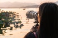 Hangzhou, China - November 9 2019: Girl photographer taking a picture with a big camera to a sunset by the West Lake Royalty Free Stock Photo