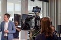 Young camerawoman with red hair films a reporter from North German local television during an interview