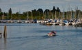 Man and boy go by motorboat across the lake to the jetty with the sailboats