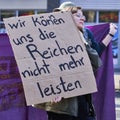 Young female demonstrator with a placard agitating against the costs for the rich at a demonstration of the trade union Verdi