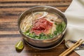 Hanoi rare Beef Pho topping with onion, noodles, green onion, lemon and coriander served in bowl isolated on wooden table top view Royalty Free Stock Photo