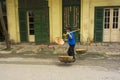 Hanoi, Vietnam - April 13, 2014: Unidentified vendor goes home with the empty baskets over old house on Hanoi str, Vietnam