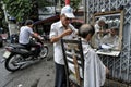 Barber shaving a man at the street.