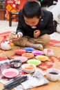 Hanoi, Vietnam - Feb 7, 2015: Schoolboy learn to paint plaster figurine by brush and color ink at Vietnamese lunar new year festiv