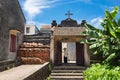 Hanoi, Vietnam - July 17, 2016: Aged church gate with Holy cross on top, Vietnamese old woman wear conical hat and stick walking i