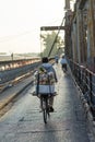 Hanoi, Vietnam - July 23, 2016: Back view of street woman vendor carrying fruit on bike on Long Bien ancient metal bridge