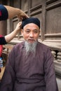 Hanoi, Vietnam - Jun 22, 2017: Old man with ancient feudal traditional long dress Ao Dai for his feudal official role in communal Royalty Free Stock Photo