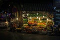 A street vendor at a colorful fruit stall illuminated by bulbs at night in the old quarter of Hanoi Royalty Free Stock Photo