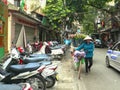 HANOI, VIETNAM - JUNE 28, 2017: a woman pushes a bicycle carrying flowers in the old quarter of hanoi Royalty Free Stock Photo