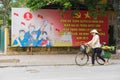 Hanoi, Vietnam - Mar 29, 2015: A vendor walking pass a communist propaganda in To Hien Thanh street