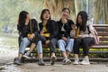 Happy young Vietnamese girls are sitting on a bench next to a lake in the center of the old city of Hanoi, Vietnam Royalty Free Stock Photo