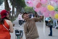 Vietnamese seller offers to buy balloons for a woman on the street in the old town of Hanoi, Vietnam