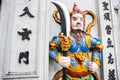 Carved replica of Asian warrior standing proud with colorful regalia holding sword