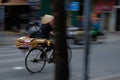 Hanoi / Vietnam, 05/11/2017: Vietnamese woman on bicycle with traditional rice hat on a busy hectic road with passing cars and