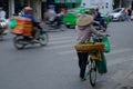 Hanoi / Vietnam, 05/11/2017: Vietnamese woman on bicycle with traditional rice hat on a busy hectic road with passing cars and