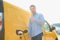 Hansome bearded guy near his new modern electric car at the charging station