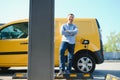 Hansome bearded guy near his new modern electric car at the charging station