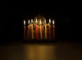 Hanukkah candles lit in a menorah on a back background
