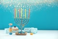 Hanukkah celebration. Menorah with burning candles, dreidels, gift boxes and donut on white wooden table against light blue Royalty Free Stock Photo